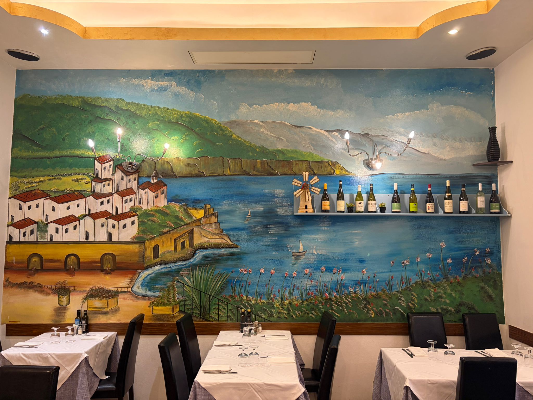 Sala interna di Amalfitana con tavoli apparecchiati e parete artistica